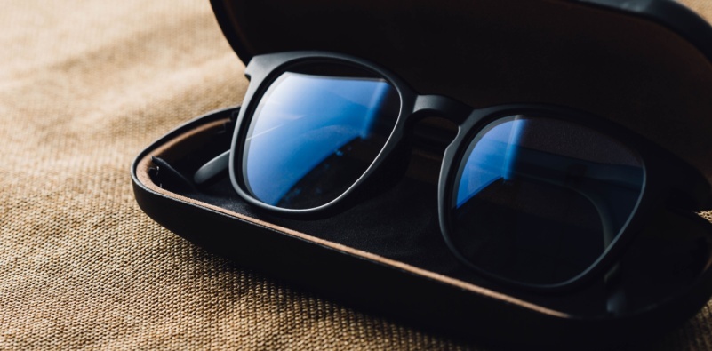 Close-up image of anti-glare glasses lenses inside their case, highlighting the reflective surface and sleek black frame.