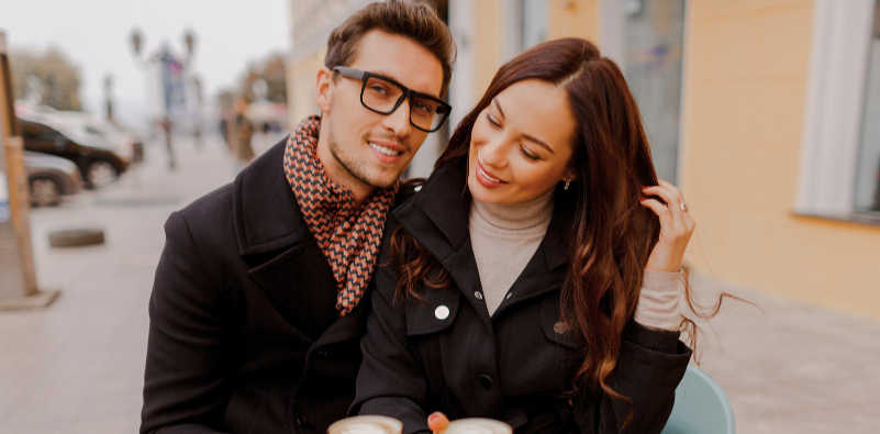 Man with girlfriend outside in winter clothing wearing glasses