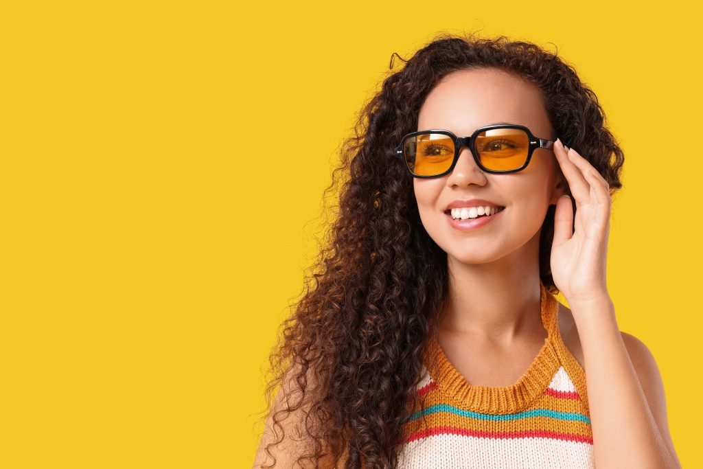 A woman wearing a pair of black oversized eyeglasses with yellow tinted lenses.