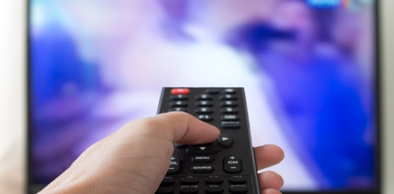 A person holding a remote pointed towards the TV