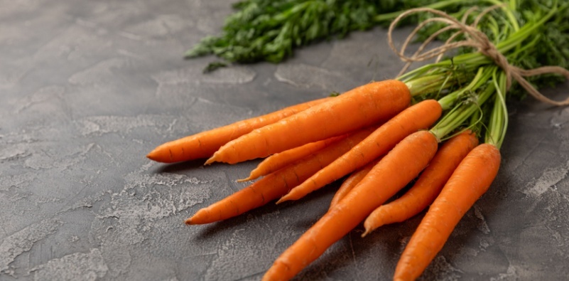 A bunch of carrots on a textured, gray surface.
