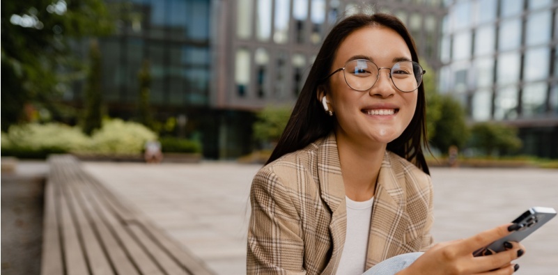 A woman outside on her phone wearing glasses